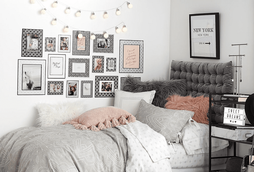 um quarto jovem bem decorado, chegio de almofadas e quadros, nos tons de cinza, preto, branco e rosa