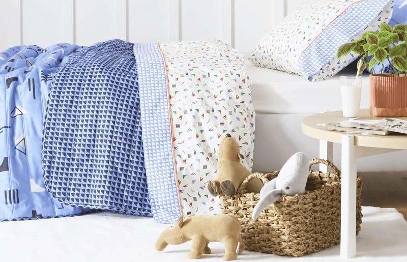 quarto infantil pequeno com brinquedos e roupa de cama em tons de azul