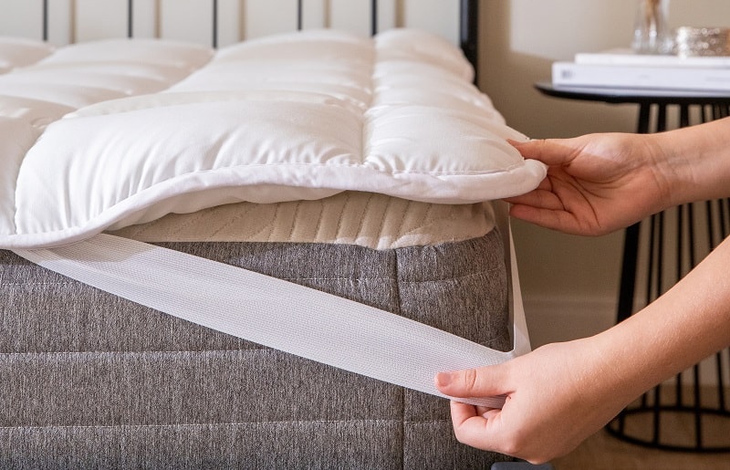 modelo de pillow top com elásticos laterais e uma pessoa encaixando no colchão